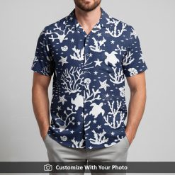 Man in tropical ocean shirt with navy and white turtle, coral and starfish on the sand