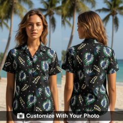 Woman wearing black Hawaiian shirt with palm leaf and floral print, navy and green tones