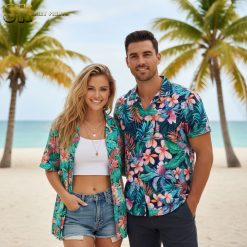 Woman sitting at outdoor cafe table wearing button-up Hawaiian shirt with tropical floral print and denim shorts