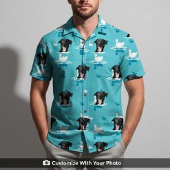 Man in blue Hawaiian shirt featuring black dog face and white swans floating on water