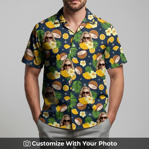 Man in navy and yellow Hawaiian shirt with face print, oranges, coconut, green leaves