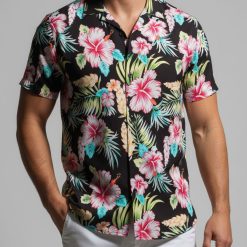 Female model in relaxed pose wearing casual Hawaiian shirt with tropical print in comfortable indoor setting