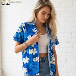 Blue and white Hawaiian shirt displaying white plumeria flowers scattered across blue fabric background