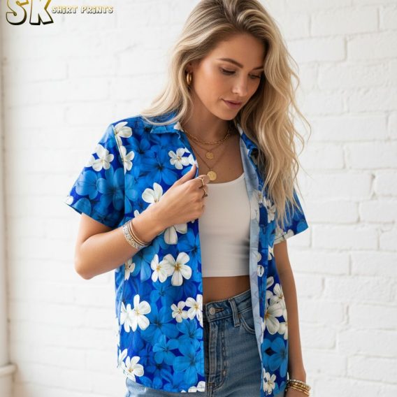 Blue and white Hawaiian shirt displaying white plumeria flowers scattered across blue fabric background