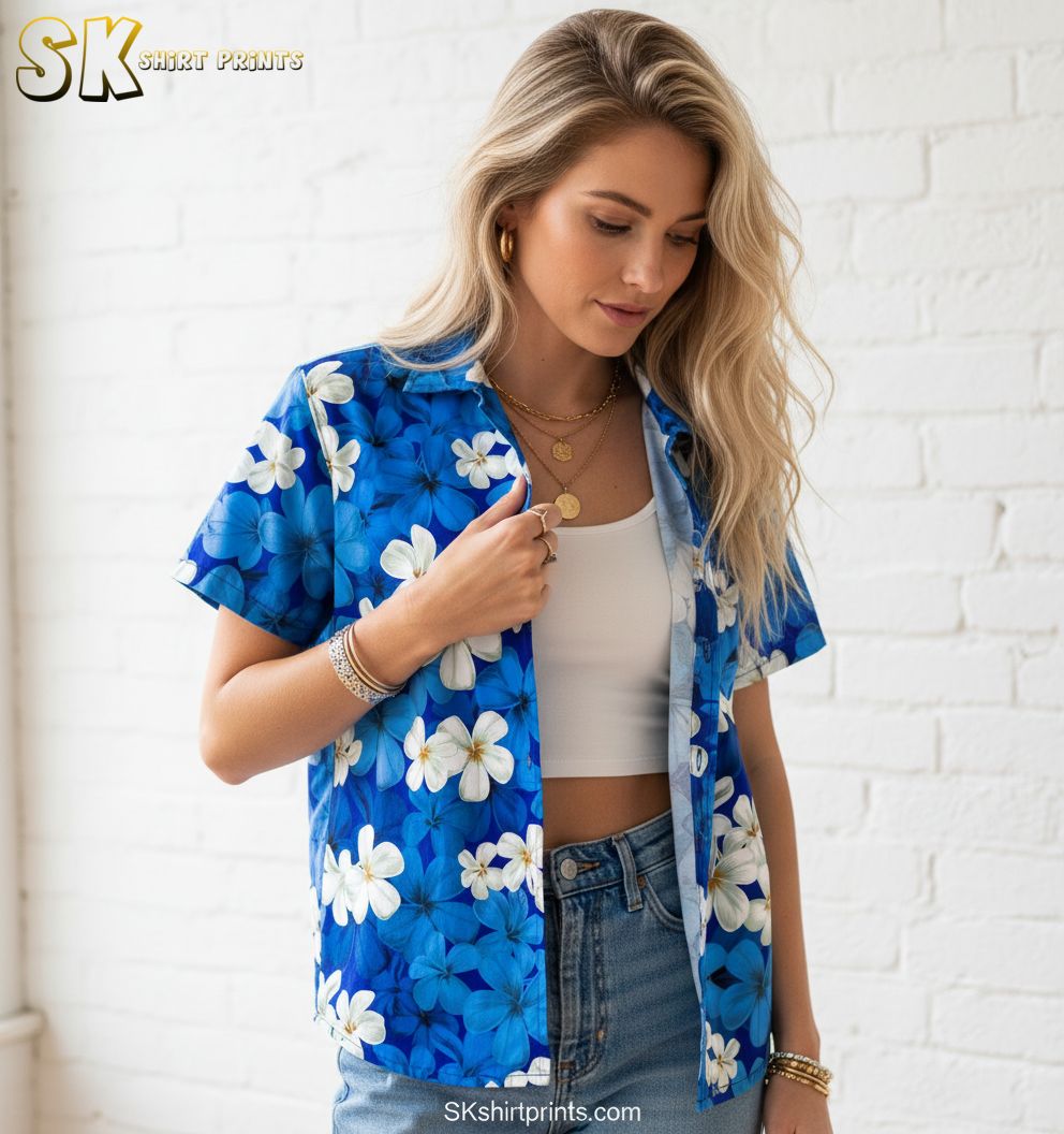 Blue and white Hawaiian shirt displaying white plumeria flowers scattered across blue fabric background