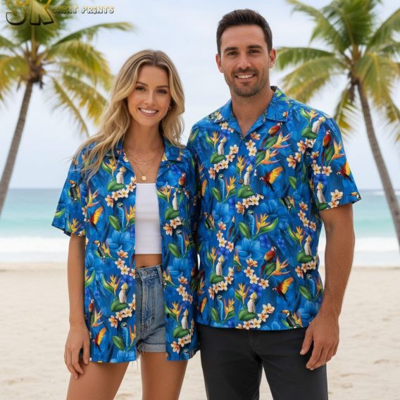 Blue floral hawaiian shirt with white plumeria flowers, orange bird-of-paradise blooms, and tropical bird motifs