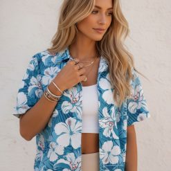 Blue tropical shirt showcasing white hibiscus flowers with tropical leaf patterns