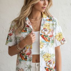 Cotton Christmas Hawaiian shirt with Santa wearing sunglasses surfing, surrounded by pink hibiscus flowers and palm trees