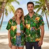 Green aloha shirt displaying colorful toucans and parrots among tropical palm leaves with sunset elements