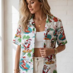 Hawaiian style Christmas shirt showing Santa Claus surfing among pink hibiscus flowers and palm trees