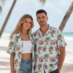 Santa Hawaiian shirt showing Santa Claus wearing Hawaiian attire while riding pink flamingo with drink in hand and palm tree backdrop