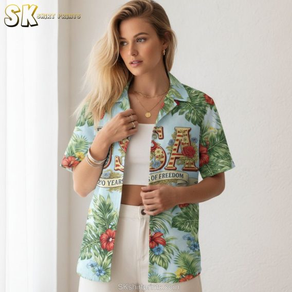 America 250 Hawaiian shirt with colorful tropical flowers in red yellow and blue, bold green leaf pattern, USA lettering with red and gold accents, and a 250 Years of Freedom banner on a light blue shirt