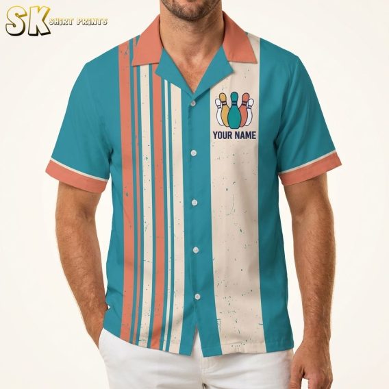 Male model wearing a Hawaiian bowling shirt with teal, orange, and off-white vertical stripes, bowling pin front graphic, and a vintage sunset bowling scene on the back with bold team name text, shot on a warm white studio background.
