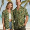 Millennium Falcon Hawaiian shirt with tiki statues, hula dancers, skulls, hibiscus flowers, and pineapples on a light green background