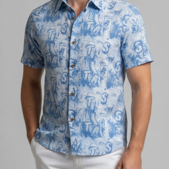 Close-up of a vintage Hawaiian shirt showing blue abstract wave and tropical artwork on a light fabric