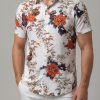 Vintage Hawaiian shirt with large rose-style red and orange flowers and dark leaf pattern on a white shirt background