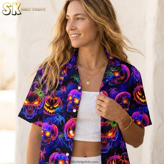 Woman wearing a Halloween Hawaiian shirt with neon glowing skulls, jack-o'-lanterns, spiders, and spider webs on dark background, airy lifestyle closeup shot showing print detail
