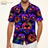 Man wearing a Halloween Hawaiian shirt with neon glowing skulls, jack-o'-lanterns, and spider webs on a dark background, photographed in studio against warm white background