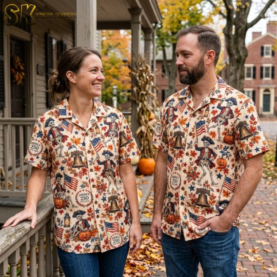 A couple wearing matching cream halloween hawaiian shirts printed with dancing colonial skeletons, Liberty Bells, pumpkins, and America 250 anniversary crests.