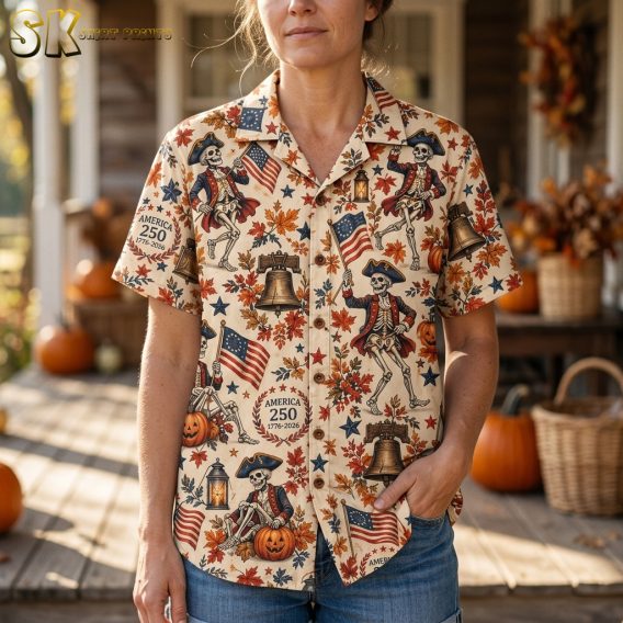 Close-up of a woman wearing the cream halloween hawaiian shirt, showing detailed artwork of colonial skeleton figures in tricorn hats alongside jack-o'-lanterns and autumn leaves.