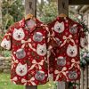 Christmas Hawaiian shirt displayed on hanger showing front and back, red background with dog and cat Santa hat portraits, bells, pine branches, and snowflakes