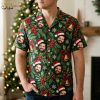 Man wearing a dark green Christmas Hawaiian shirt with a Santa hat face and holiday motif print in a lifestyle setting