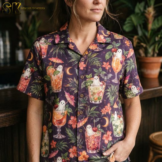 Close-up of a woman wearing a dark purple spooky hawaiian shirt, showing detailed artwork of ghost figures inside colorful tropical cocktails with fruit garnishes and paper umbrellas.