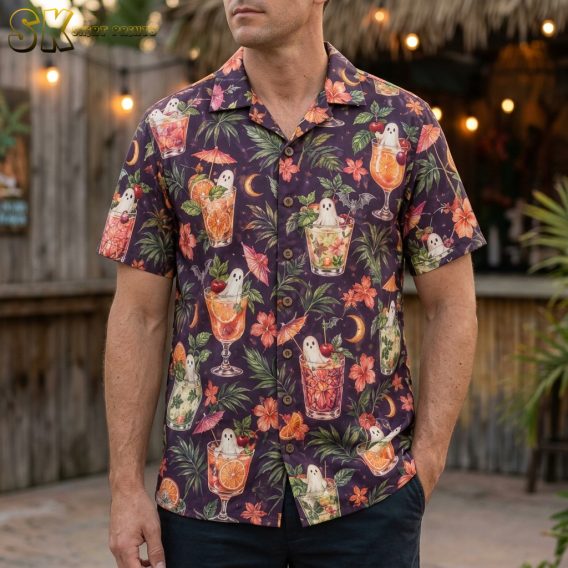 A man wearing a dark purple mens halloween hawaiian shirt printed with tropical cocktail glasses containing white ghosts, orange hibiscus flowers, and small black bats.
