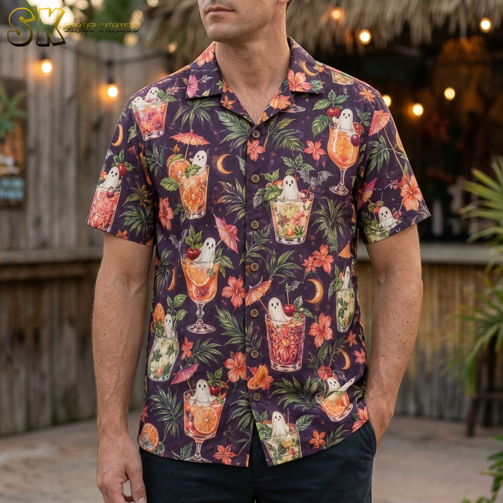 A man wearing a dark purple mens halloween hawaiian shirt printed with tropical cocktail glasses containing white ghosts, orange hibiscus flowers, and small black bats.