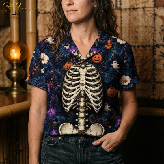 Female closeup of halloween tiki shirt showing detailed pattern of jack-o'-lanterns, ghosts, tropical flowers, crescent moons, and stars on dark blue fabric