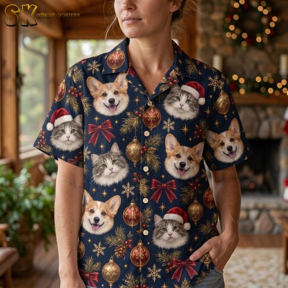 Woman wearing a Hawaiian Christmas shirt womens style, closeup view showing corgi and cat faces in Santa hats with gold ornaments and red bows on dark blue fabric