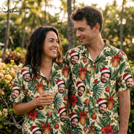 Couple wearing matching Hawaiian Christmas shirts with tropical Santa hat face print, hibiscus, pineapples, and red ornaments on beige