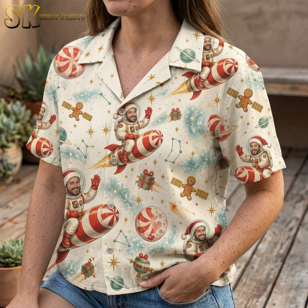 Closeup of a woman wearing a Hawaiian style Christmas shirt showing detailed astronaut Santa, candy cane rocket, gingerbread men, planets, and stars print in red, green, and cream