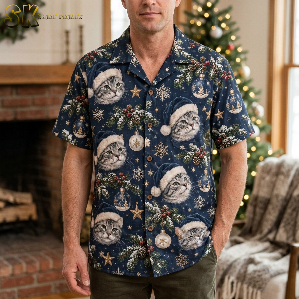 Male model wearing a dark blue mens Christmas aloha shirt with cats in Santa hats and holiday motifs including snowflakes and gold stars