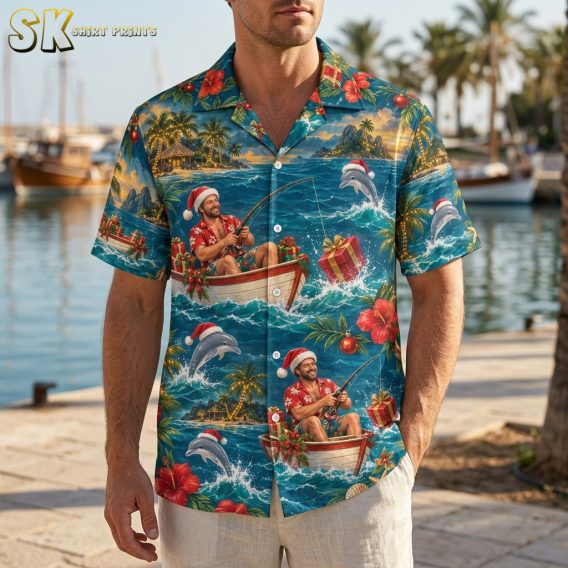 Man wearing a mens christmas hawaiian shirt with Santa fishing, dolphins, and tropical holiday motifs in blue, red, and green