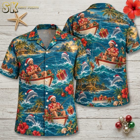 Flat lay of mens hawaiian christmas shirt showing front and back with Santa fishing from a boat, leaping dolphins, hibiscus flowers, Christmas ornaments, and palm trees on blue fabric