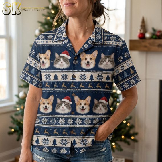 Close-up view of a tropical Christmas shirt fabric showing detailed dog and cat faces wearing Santa hats with snowflakes and Christmas tree motifs on navy blue