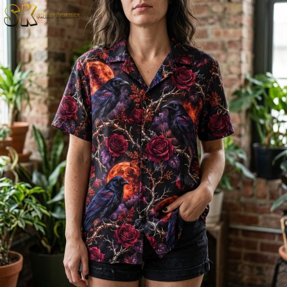 Close-up of a spooky hawaiian shirt showing detailed artwork of iridescent crows on gnarled branches, deep red roses, and orange blood moons on a black background.