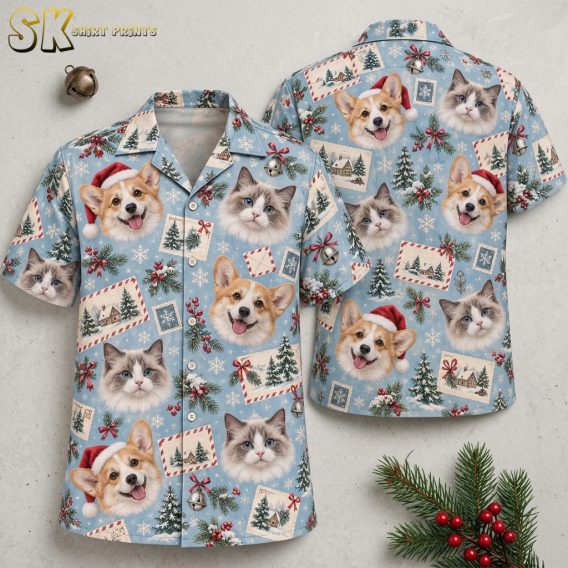 Flat lay of a tropical Santa shirt showing front and back with corgi dogs in Santa hats, cats, Christmas trees, holly, and snowflakes on a light blue background