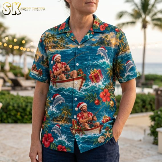 Close-up of xmas hawaiian shirt print showing Santa in a Santa hat fishing from a boat, leaping dolphins, hibiscus flowers, Christmas ornaments, and wrapped gifts