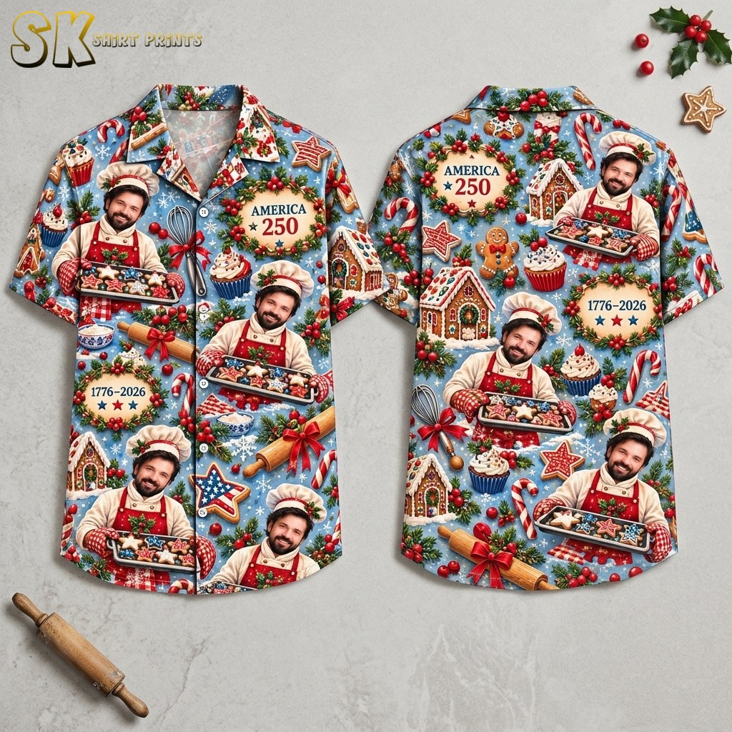 Front and back of a light blue short-sleeve button-up shirt displayed on a flat surface, showing a repeating pattern of a smiling chef holding star-shaped cookies alongside gingerbread houses, candy canes, and wreaths reading 'AMERICA 250' and '1776–2026'.