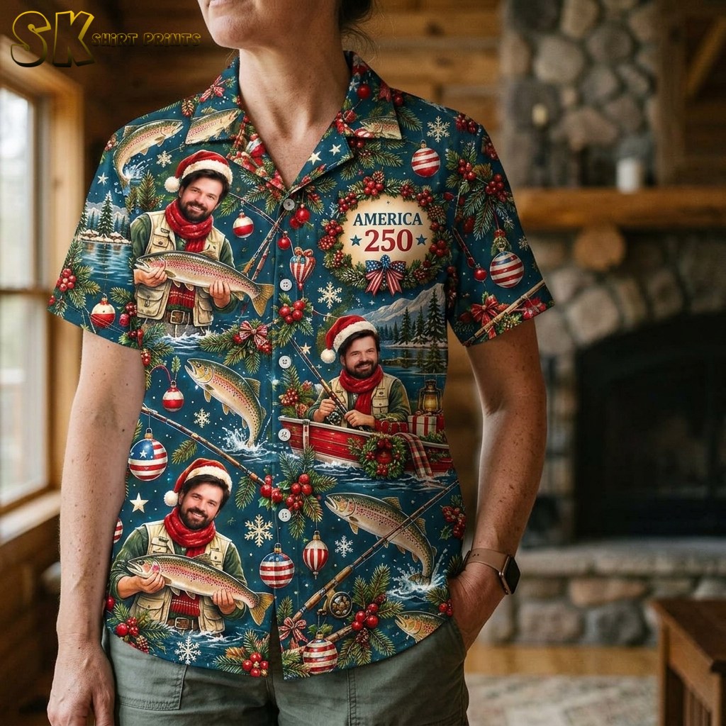 A close-up view of a woman wearing the deep blue Christmas fishing Hawaiian shirt, highlighting the detailed illustration of the Santa-hat fisherman, American flag ornaments, snowflakes, and the 'AMERICA 250' wreath text element at near range.