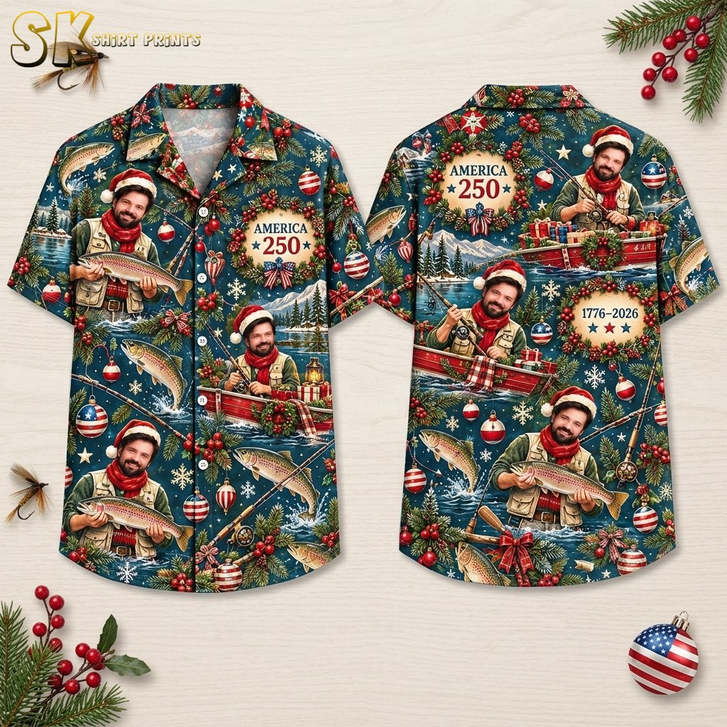 Front and back hanger view of a deep blue short-sleeve button-up shirt covered in an all-over print featuring a Santa-hat-wearing fisherman in a red boat, evergreen branches with red berries, American flag ornaments, snowflakes, and the text 'AMERICA 250' and '1776 – 2026' inside a Christmas wreath.