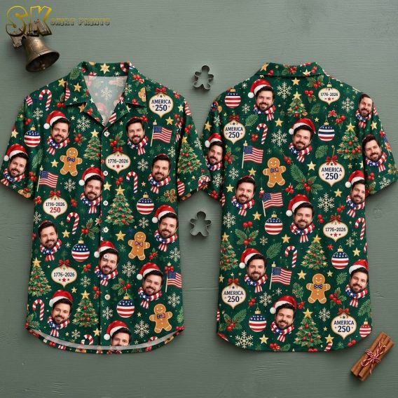 Front and back hanger view of a dark green short-sleeve button-up shirt covered in a dense all-over pattern of a smiling bearded man in a Santa hat and American flag scarf, gingerbread men, decorated Christmas trees, and ornaments printed with AMERICA 250 and 1776-2026, accented by candy canes, American flags, snowflakes, gold stars, and red-white-and-blue baubles.