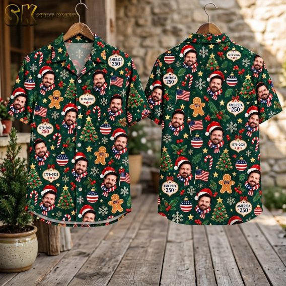 Flat-lay view of the shirt's front and back panels laid out on a surface, showing the full spread of the dark green all-over pattern including American flags, Christmas trees, snowflakes, red-white-and-blue baubles, and AMERICA 250 ornaments.