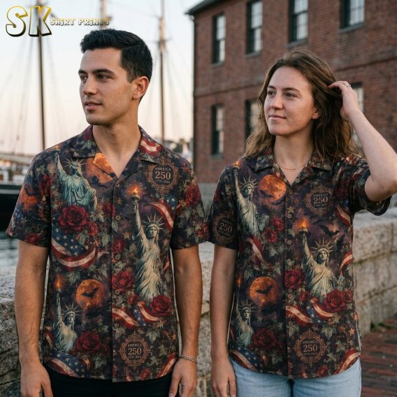 Couple lifestyle shot featuring the halloween hawaiian shirt with Statue of Liberty, orange moons, bats, and America 250 labels on a dark base.