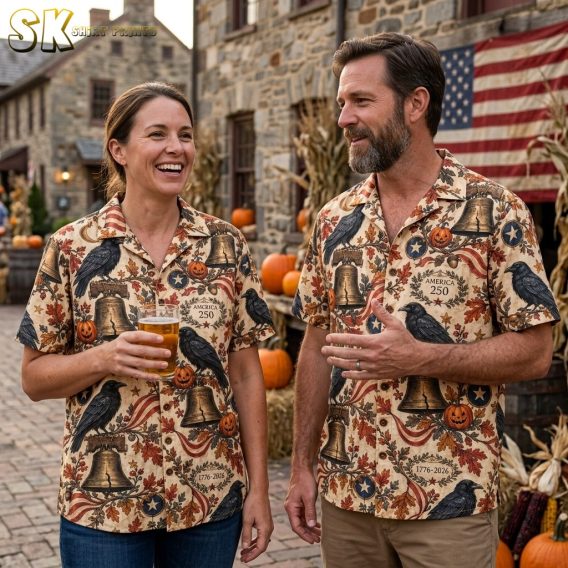 Couple wearing matching halloween hawaiian shirts featuring ravens, Liberty Bells, jack-o'-lanterns, and America 250 wreaths on a beige ground.