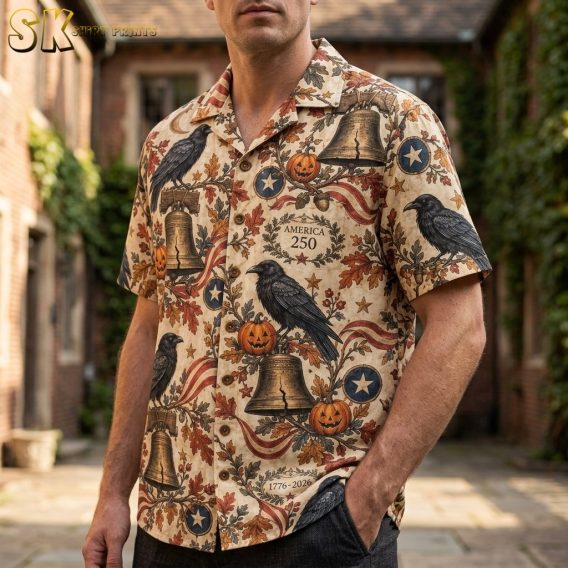 Man wearing a mens halloween hawaiian shirt printed with ravens, Liberty Bells, pumpkins, and America 250 wreaths on a beige background.