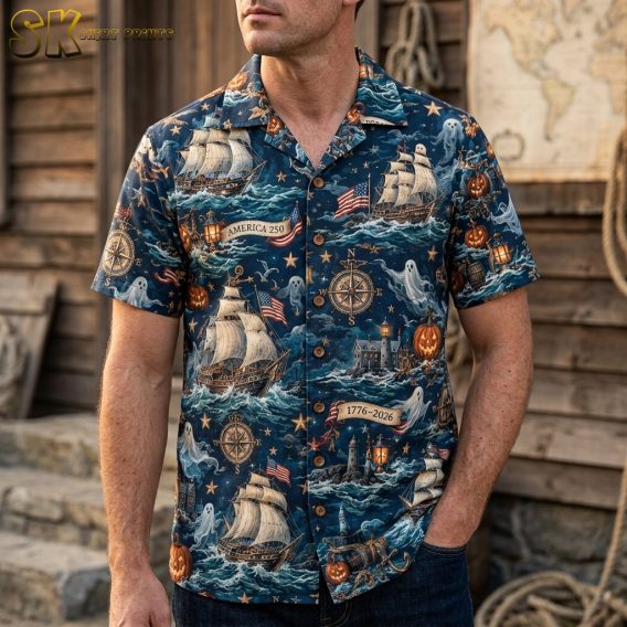 A man wearing the navy blue America 250 Hawaiian shirt, showing the all-over pattern of sailing ships, ghost figures, and pumpkins as it fits on a male frame.
