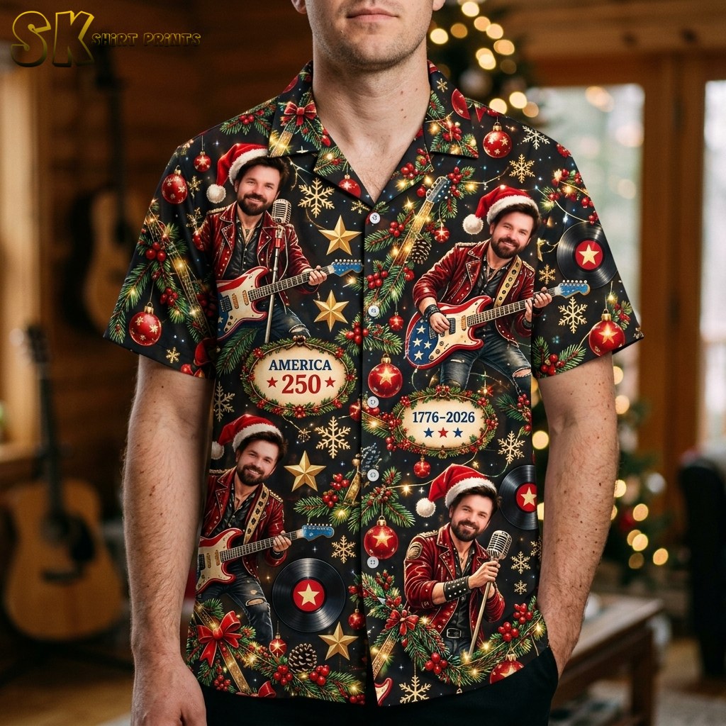 A man wearing the black short-sleeve button-up shirt featuring a repeating pattern of a Santa-hat-wearing musician, Christmas decorations, and America 250 anniversary text.